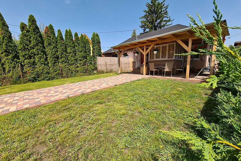 Holzhaus mit Garten, Bäumen und grünem Rasen.