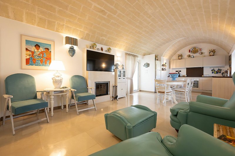 Trulli Le Pupe - Kitchen and living room with TV area and armchairs