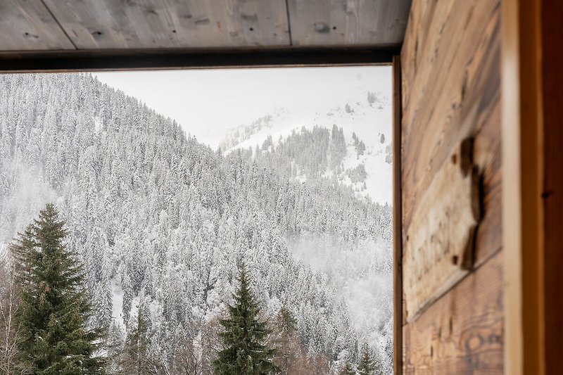 Ein winterliches Holzhaus mit verschneitem Dach und Fenstern.