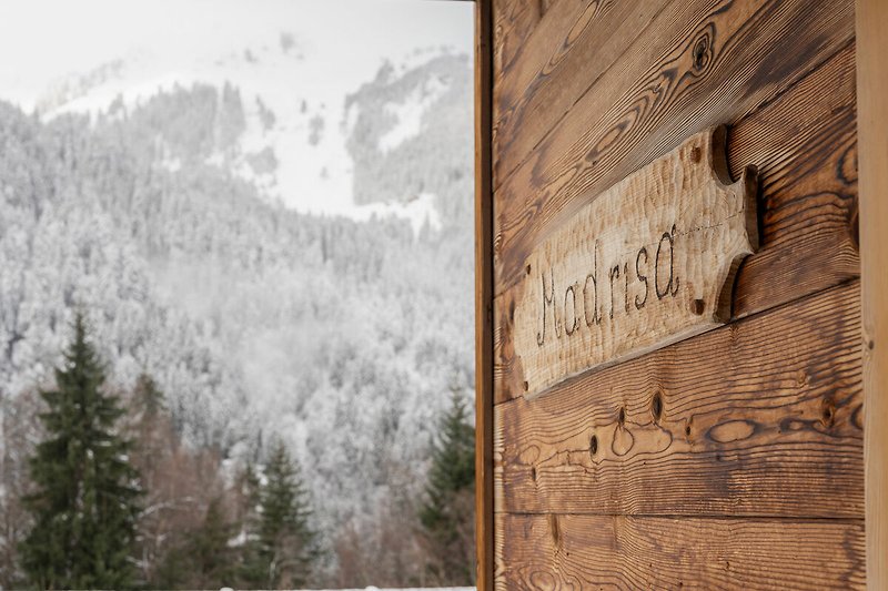 Holzhaus mit Bergblick und winterlicher Landschaft.