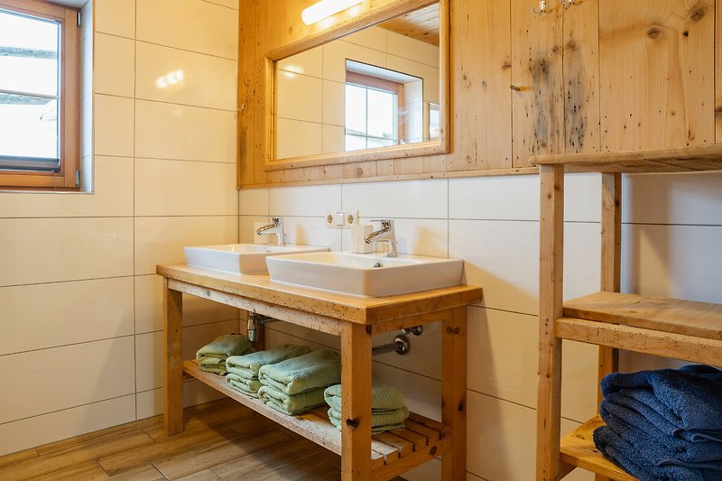 Badezimmer mit Spiegel, Waschbecken und Holzakzenten.