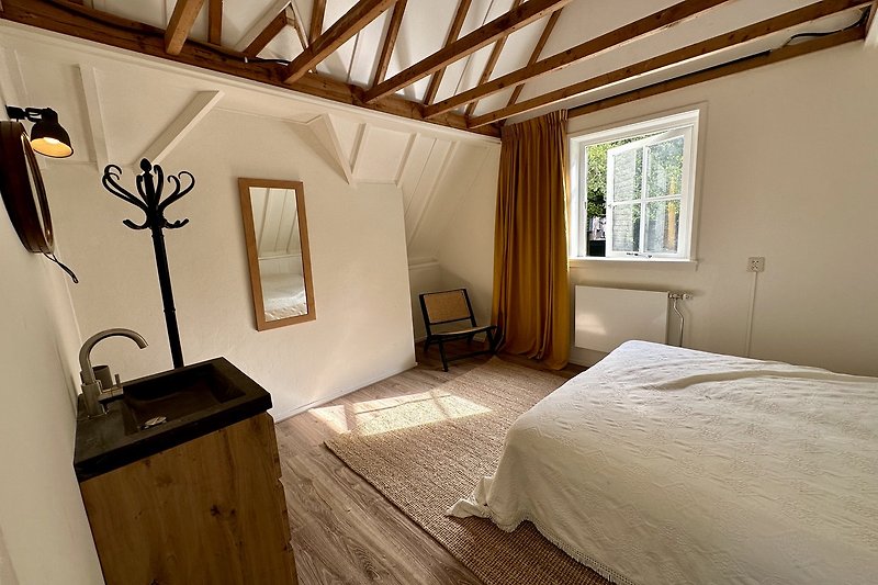 Gemütliches Zimmer mit Holzmöbeln, Fenster und bequemem Bett.