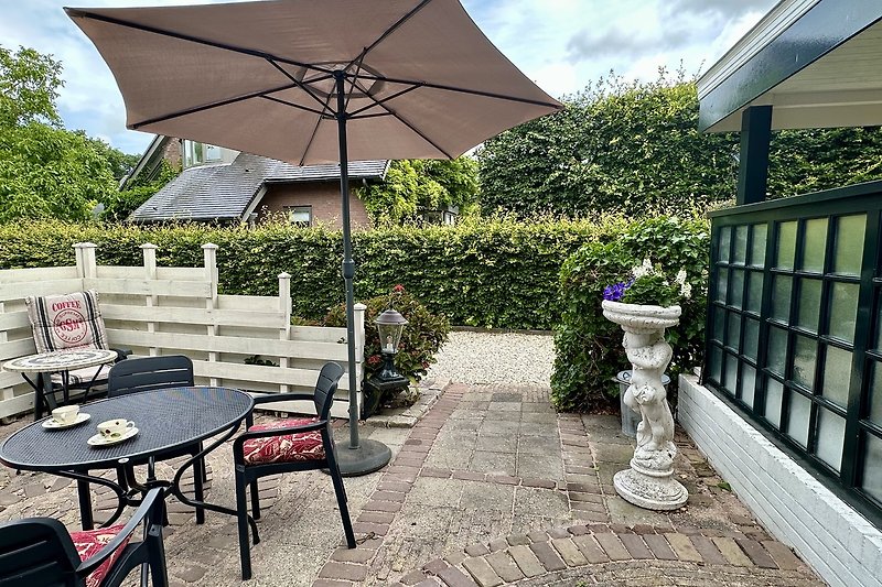 Schöne Terrasse mit Pflanzen, Tisch und Sonnenschirm.