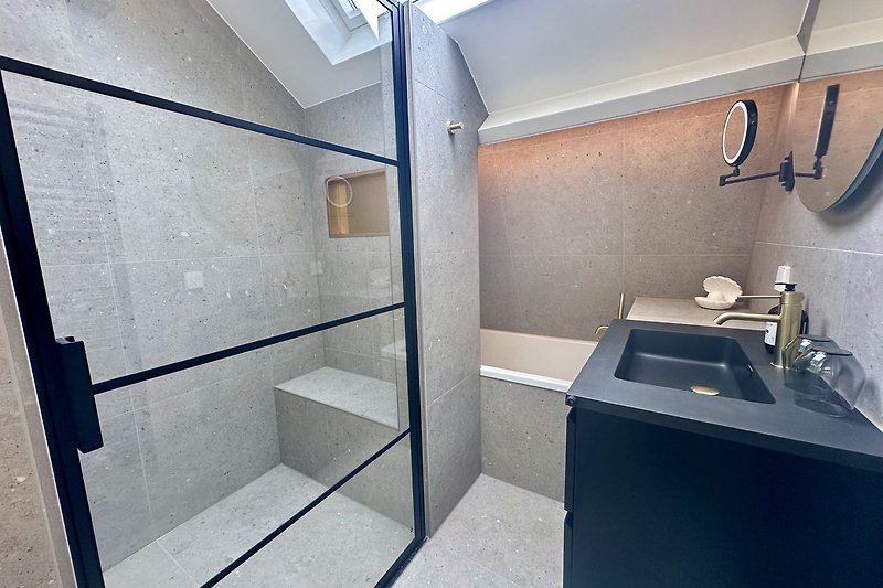 Modernes Badezimmer mit Glasdusche und Spiegel.