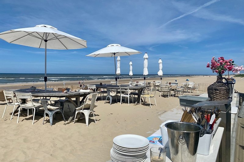 Strand mit Sonnenschirmen, Palmen, Tisch und Stühlen. Erfrischende Aussicht.