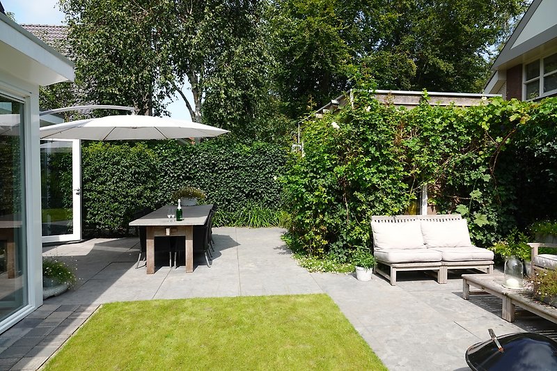 Einladender Außenbereich mit Gartenmöbeln und schattigem Baum.