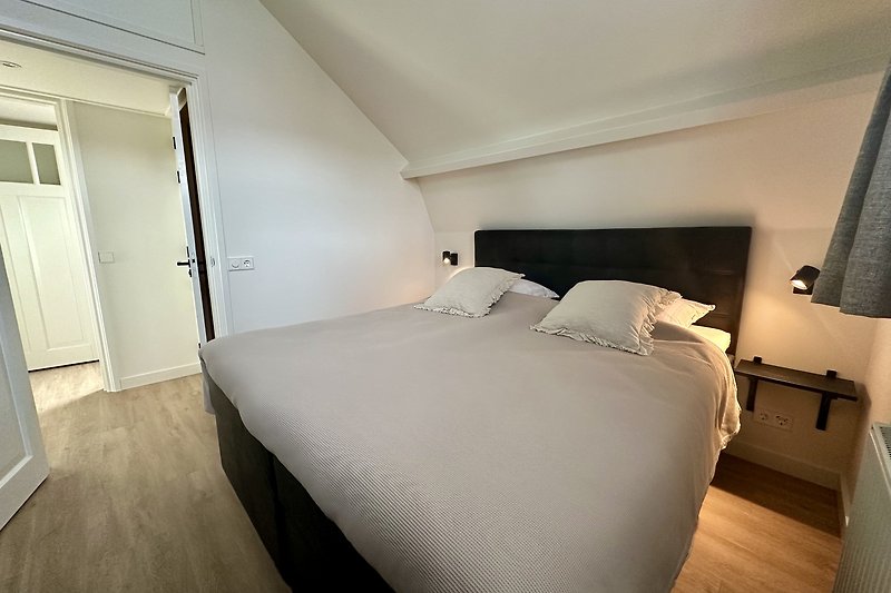 Schlafzimmer mit elegantem Holzbett und stilvoller Beleuchtung.