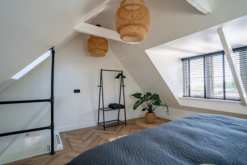 Gemütliches Schlafzimmer mit Holzboden und stilvoller Beleuchtung.