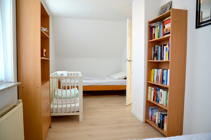 Stilvolles Schlafzimmer mit Bücherregal, Fenster und gemütlichem Bett.