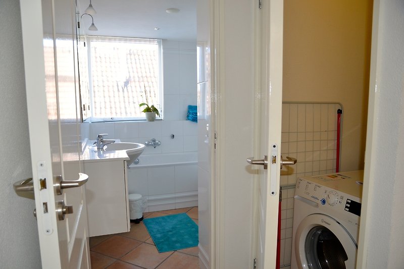 Modernes Badezimmer mit Spiegel, Waschbecken und Waschmaschine.