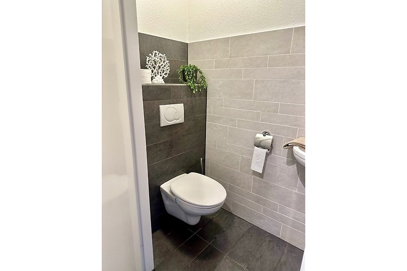 Willkommen in diesem stilvollen Badezimmer mit lila Akzenten und modernen Armaturen. Entspannen Sie sich und genießen Sie den Komfort!