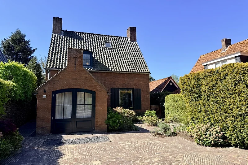 Historisches Backsteinhaus mit gepflegtem Vorgarten und Einfahrt.