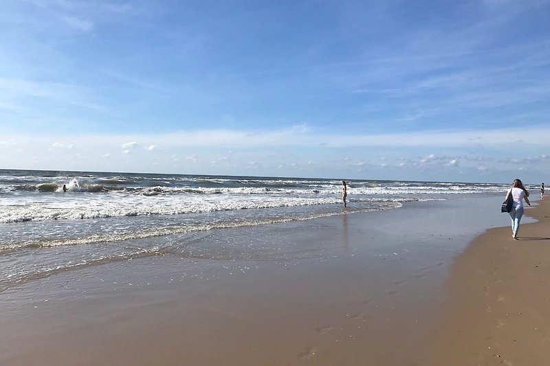 Strand mit Menschen, Meer, Wellen und Himmel.
