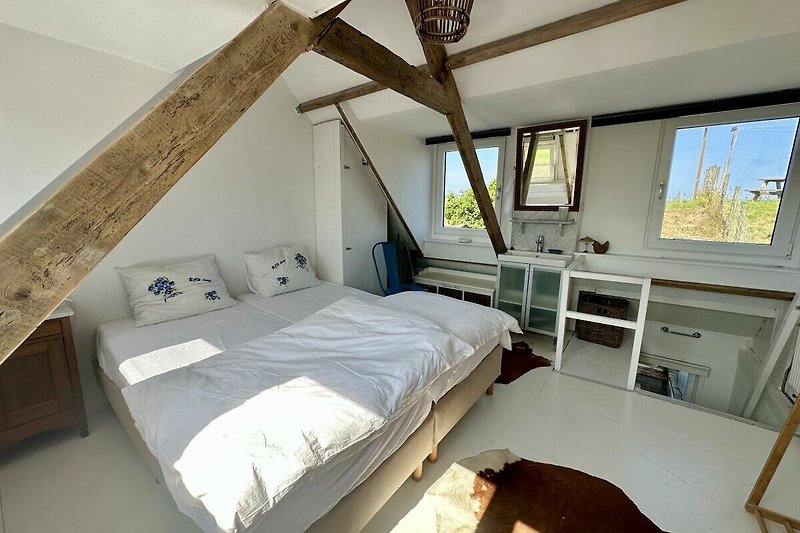 Gemütliches Schlafzimmer mit Holzbett, Kissen und Fenster. Erholung und Komfort in dieser Ferienwohnung.