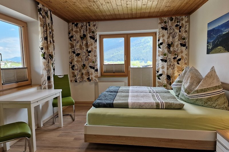 Gemütliches Zimmer mit Holzmöbeln, blauen Vorhängen und bequemem Bett.