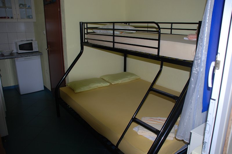 Gemütliches Zimmer mit Etagenbett, Bettwäsche und Mikrowelle.