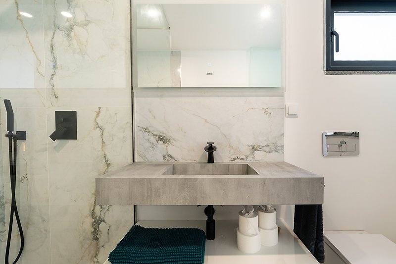 weiteres Badezimmer mit Spiegel, Waschbecken und Dusche. Einladendes Interieur.