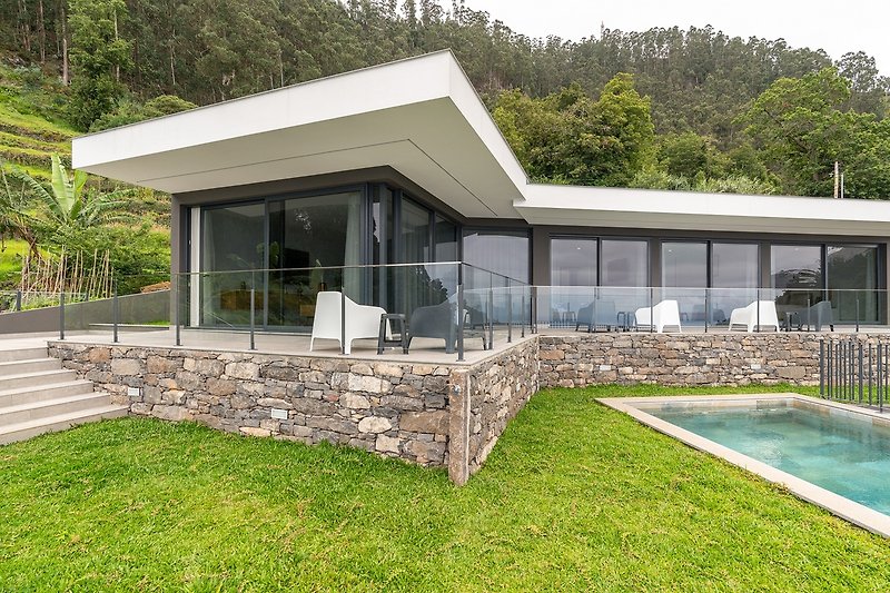 Schönes Haus mit Pool, grünem Garten und stilvollem Design.