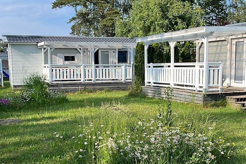 Ländliches Ferienhaus mit Garten, Veranda und blühenden Pflanzen.