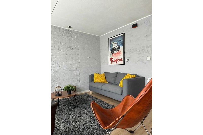 Wohnzimmer mit bequemer Couch, Holzmöbeln und Pflanzen.