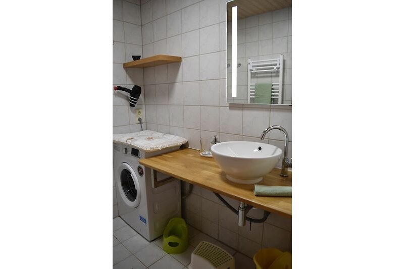 Hochparterre: Gemütliches Badezimmer mit stilvollem Waschbecken und Spiegel.
