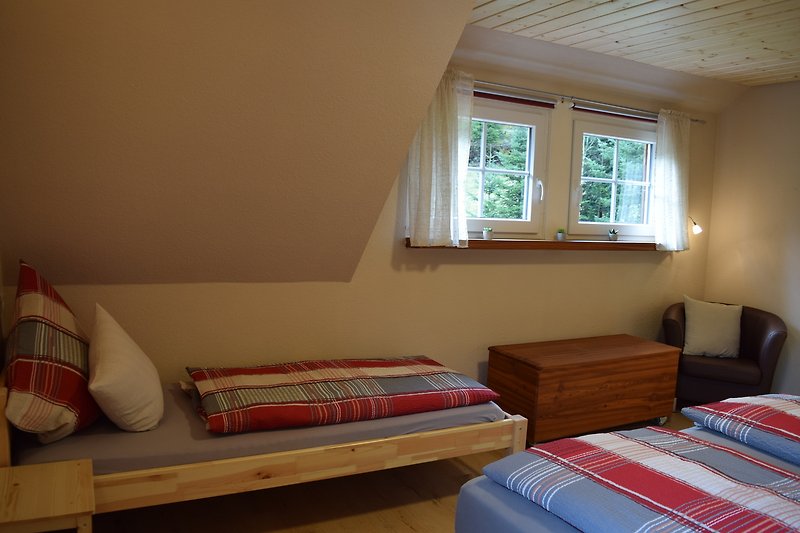 Sxhlafzimmer  mit Holzmöbeln, gemütlichem Boxspringbett  und Fensterblick.