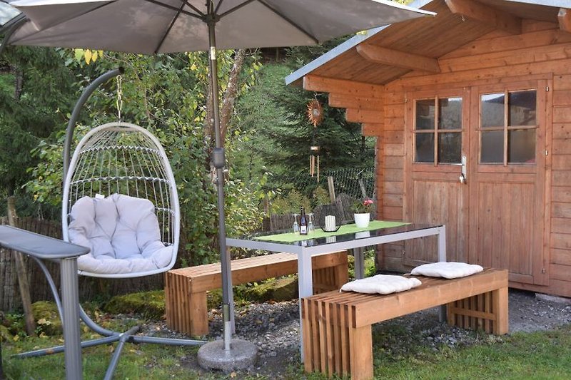 Holzmöbel, Tisch, Stühle , Relaxsessel und Sonnenschirm im Garten.