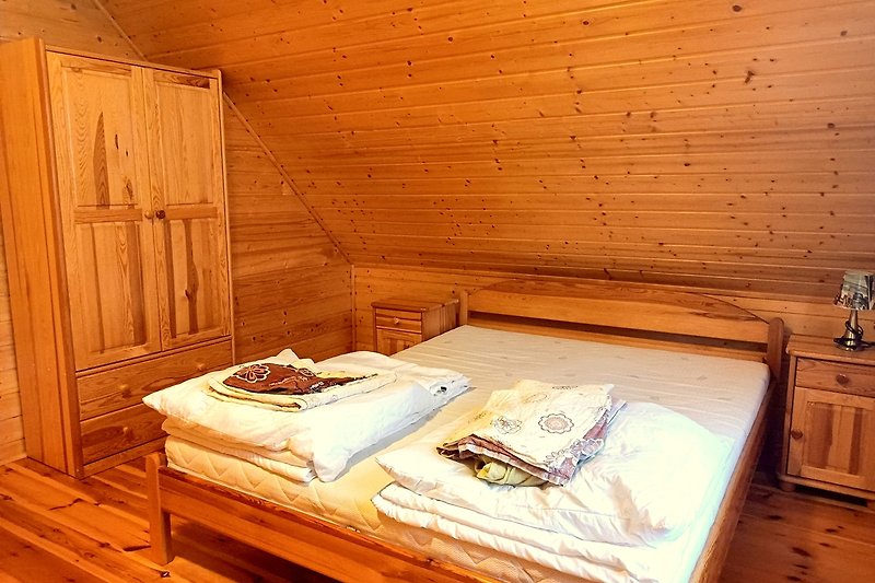 Gemütliches Schlafzimmer mit Holzmöbeln und Fensterblick. Gemütliches Bett und Schrank.