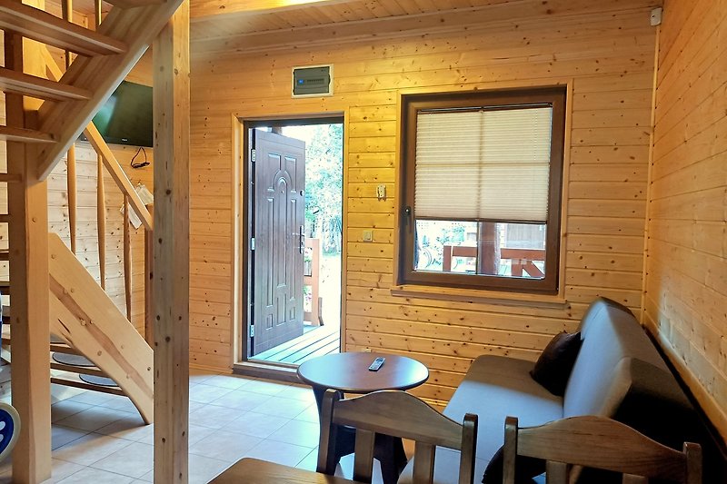 Wohnzimmer mit Holzmöbeln, großen Fenstern und gemütlicher Einrichtung.