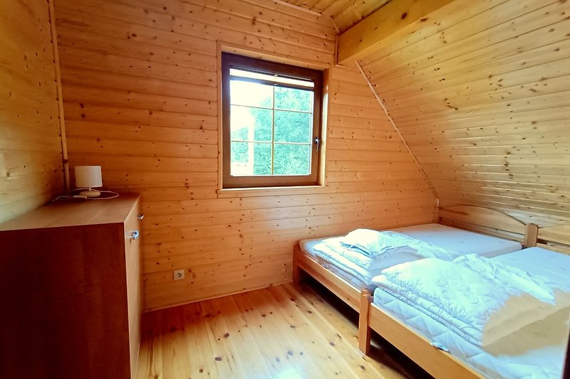 Gemütliches Schlafzimmer mit Holzmöbeln, Bett und Fensterblick. Gemütliches Ambiente.