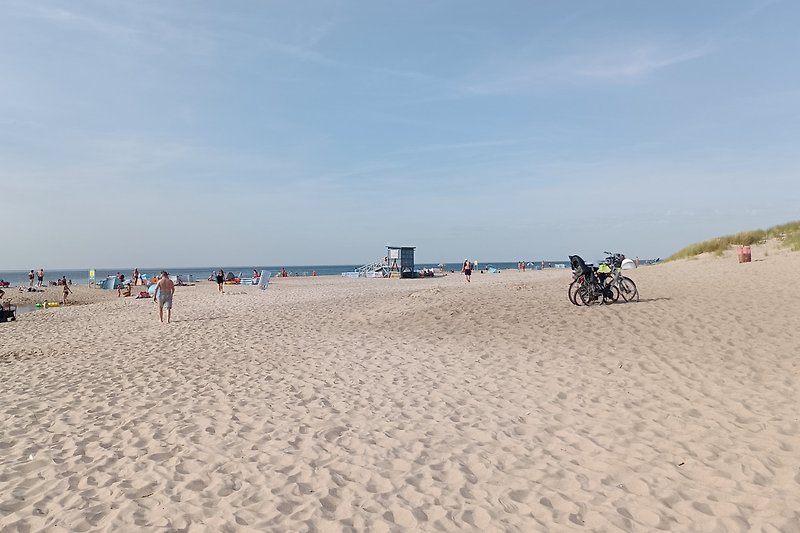 Schönes Ferienhaus am Strand mit Fahrrädern und fröhlichen Menschen. Genießen Sie Ihren Urlaub!