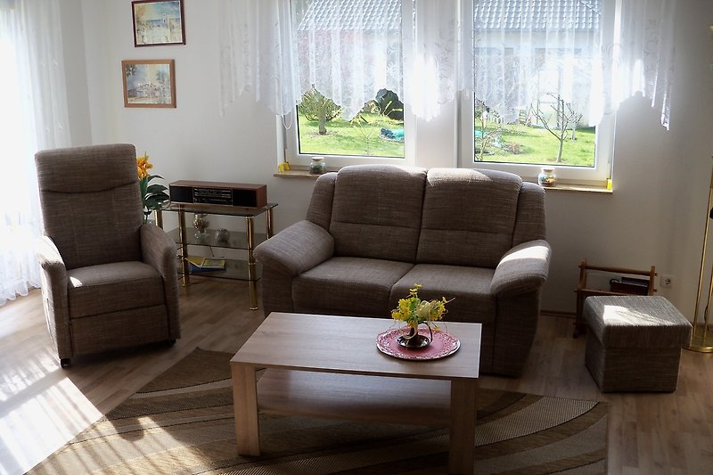 Wohnzimmer mit gemütlicher Couch, Tisch und Fenster.