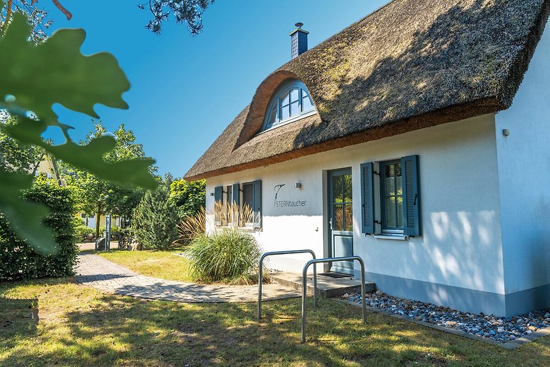 Charmantes Landhaus mit Reetdach, Holzfassade und grünem Garten.