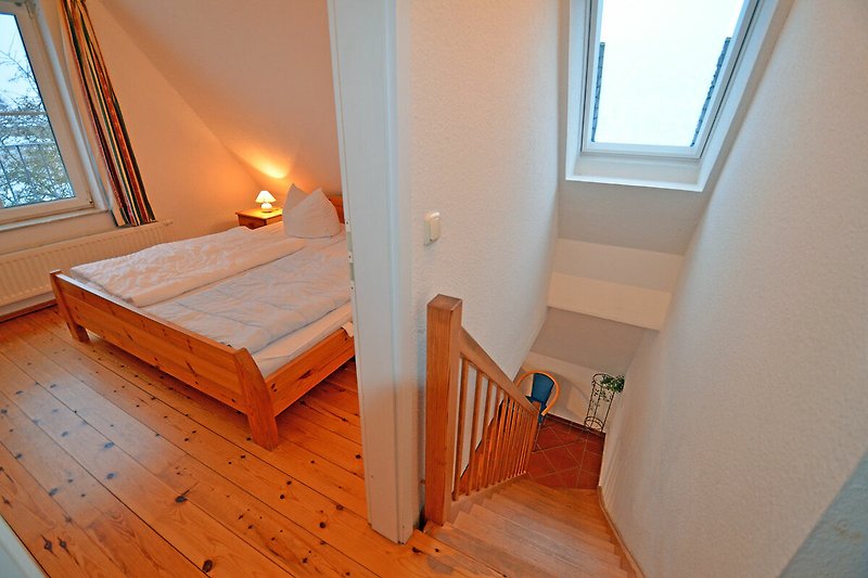 Gemütliches Schlafzimmer mit Holzboden und Fenster.