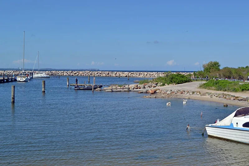 Direkter Blick auf Meer, Sandstrand, Boote und Yachthafen.