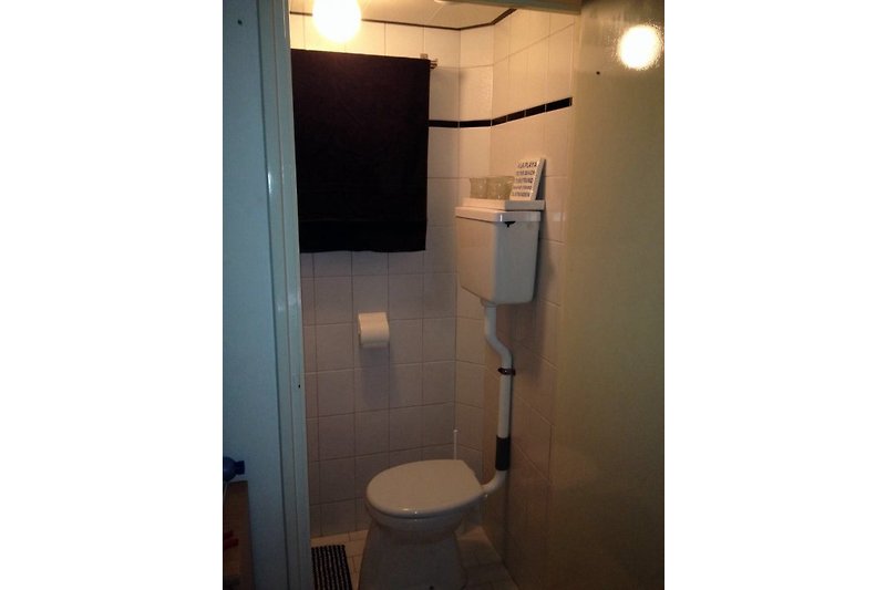 De badkamer bevindt zich op de begane grond met douche en toilet. De wastafel met spiegel zit in de grote slaapkamer.