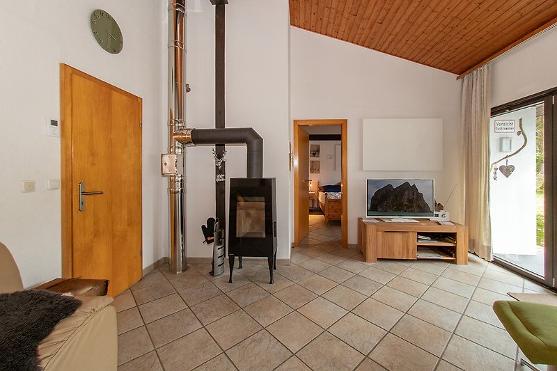 Wohnzimmer mit Holzbalken, gemütlicher Einrichtung und Hauspflanze.