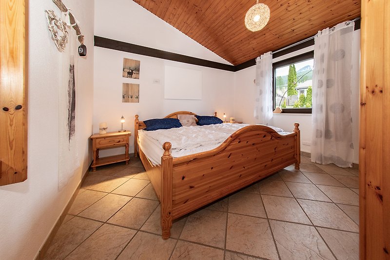 Gemütliches Schlafzimmer mit Holzbett und Fensterblick.