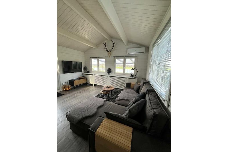 Modernes Wohnzimmer mit bequemer Couch, Holzmöbeln und großem Fenster.