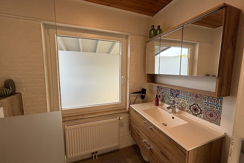 Modernes Badezimmer mit Spiegel, Waschbecken und Schrank.