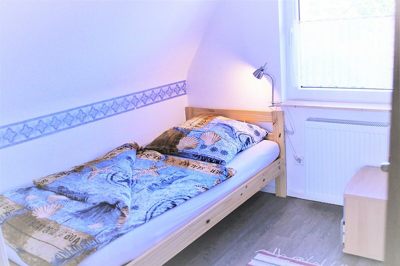 Schlafzimmer mit bequemem Bett, Holzmöbeln und blauer Bettwäsche.