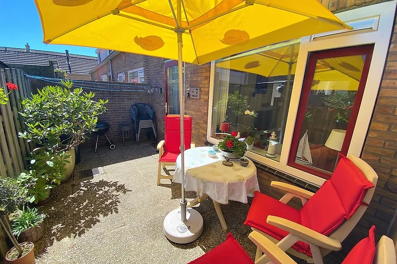 Gemütliche Terrasse mit Möbeln, plantzen, Tisch und Sonnenschirm.