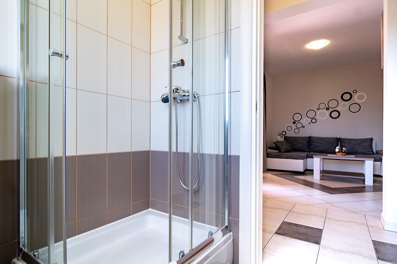 Moderne Badezimmerausstattung mit Glasdusche und Metallarmaturen.