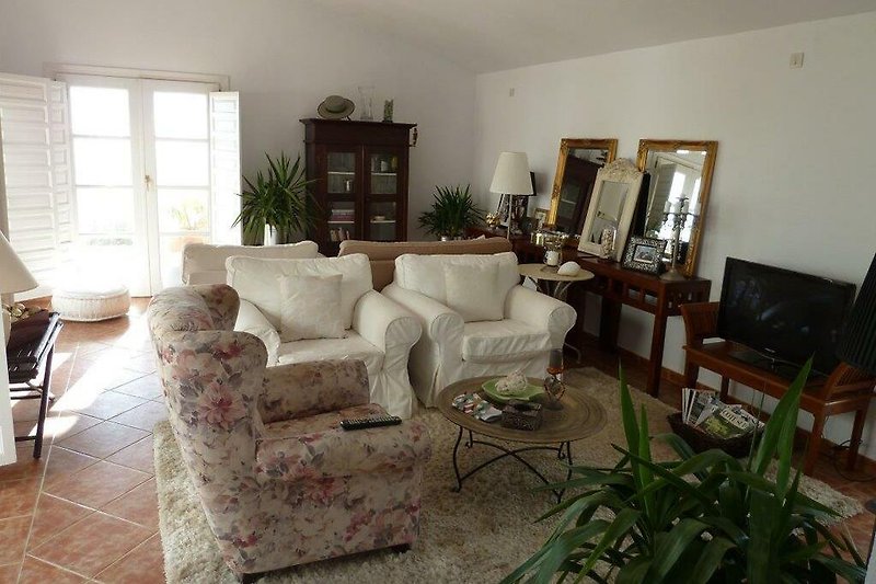 Wohnzimmer mit stilvollen Möbeln, Pflanzen und großem Fenster.