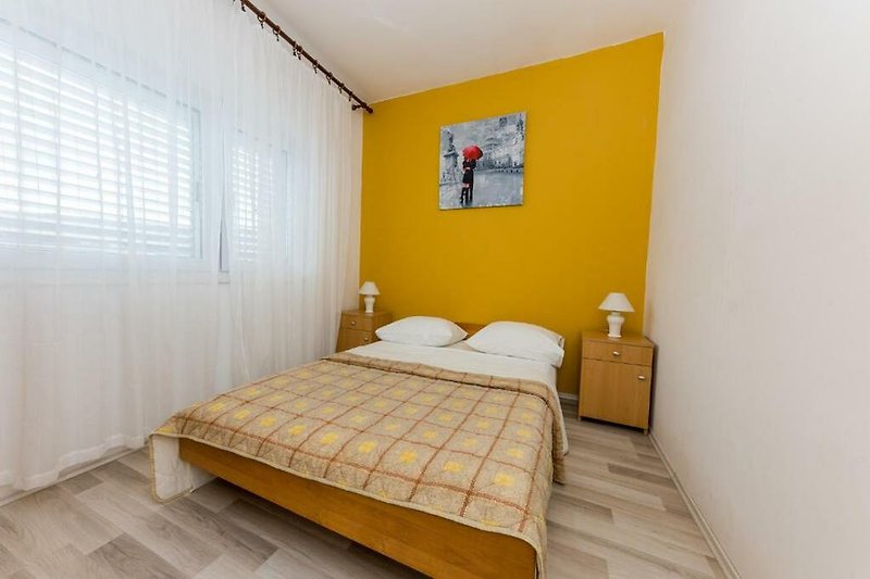 Stilvolles Schlafzimmer mit orangefarbenem Bett und Holzwand.