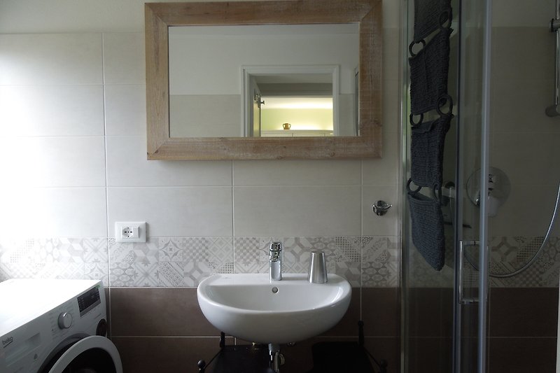 Bagno luminoso con lavabo moderno, specchio e rubinetto.