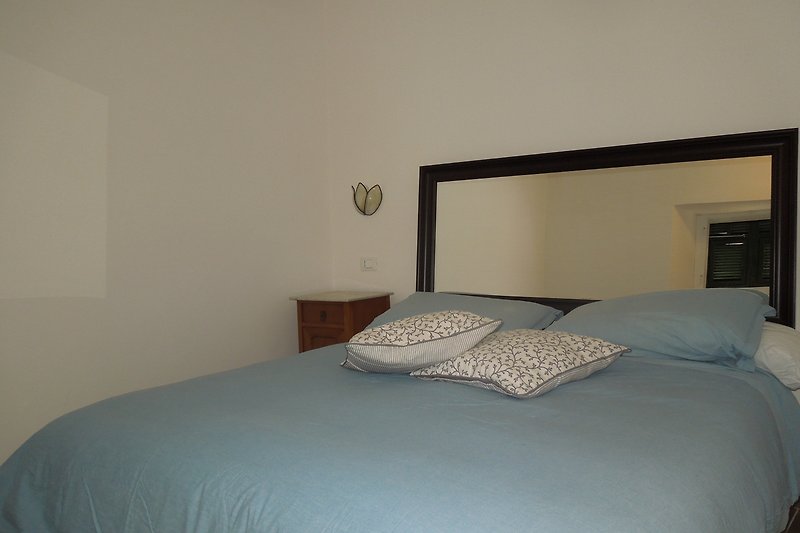 Elegante camera da letto con letto in legno, lampada e specchio.