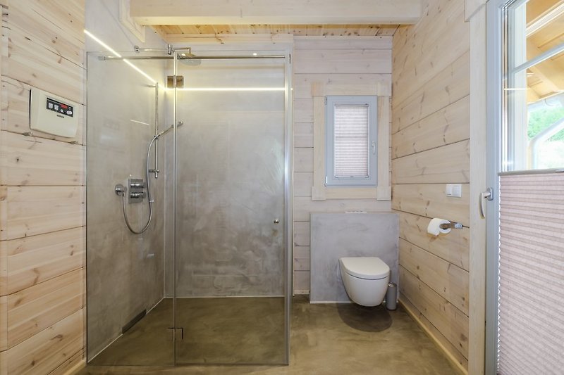 stijlvolle brede regendouche met glazen wanden, direct ernaast de Finse sauna