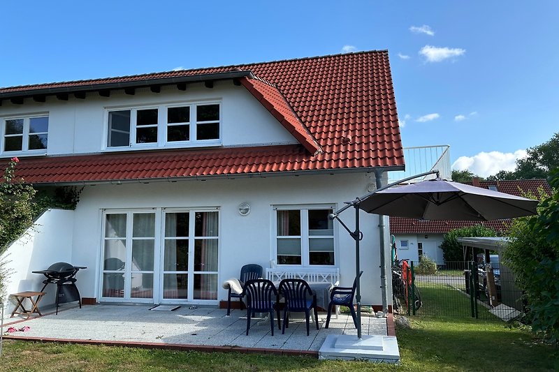 Gemütliche Veranda mit Gartenmöbeln und Blick auf gepflegten Rasen.