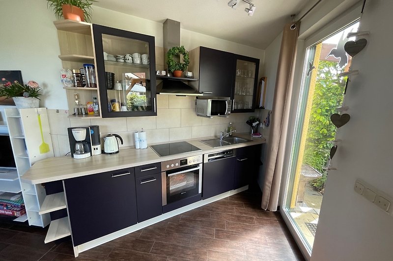 Moderne Küche mit stilvoller Einrichtung und großen Fenstern.